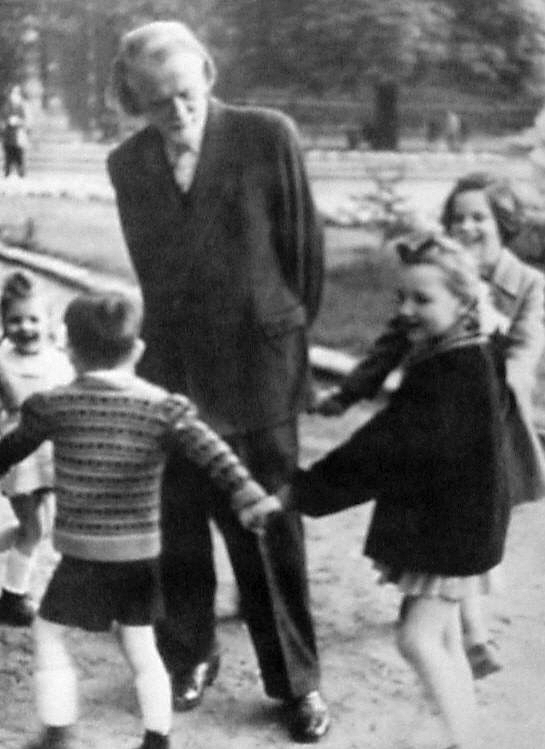 Zoltan Kodaly standing in the middle of a circle of young children playing a singing game